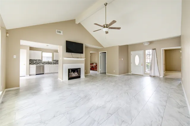 a view of a livingroom with a fireplace a ceiling fan and windows