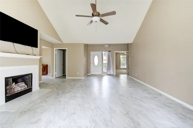a view of a livingroom with a fireplace a ceiling fan and table in a room