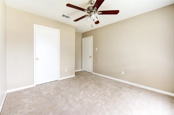 an empty room with a ceiling fan and carpet