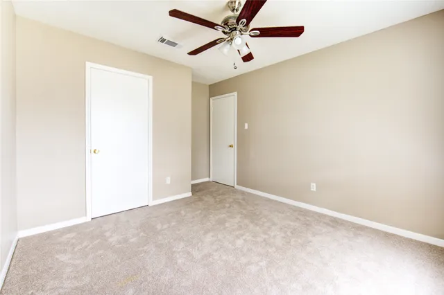 an empty room with a ceiling fan and carpet