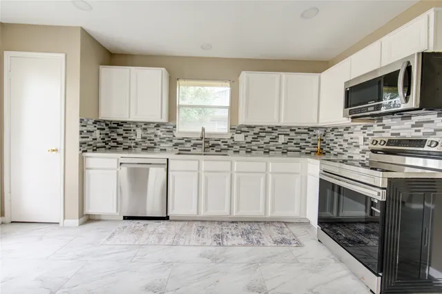 a kitchen with white cabinets sink and stainless steel appliances