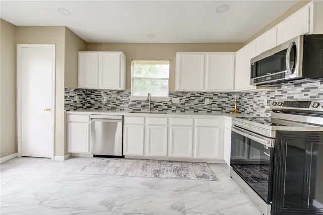 a kitchen with stainless steel appliances granite countertop a stove a sink and a microwave
