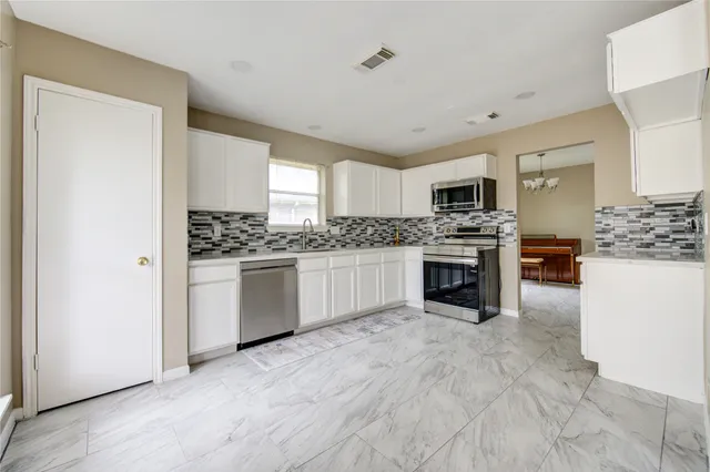 a kitchen with granite countertop a stove top oven and refrigerator