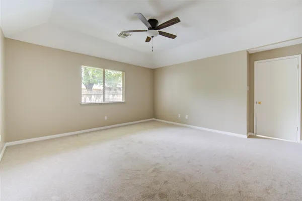 an empty room with windows and fan