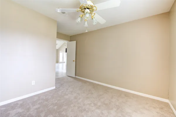 a view of an empty room with chandelier fan