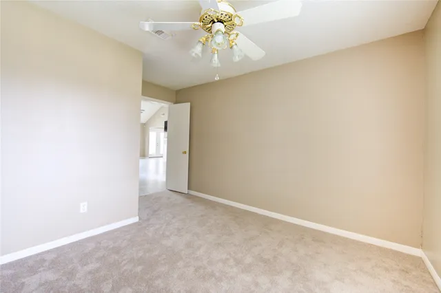 a view of an empty room with chandelier fan