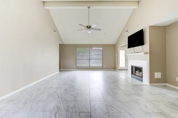 a view of a livingroom with a fireplace a ceiling fan and windows
