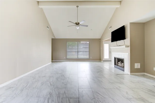 a view of a livingroom with a fireplace a ceiling fan and windows