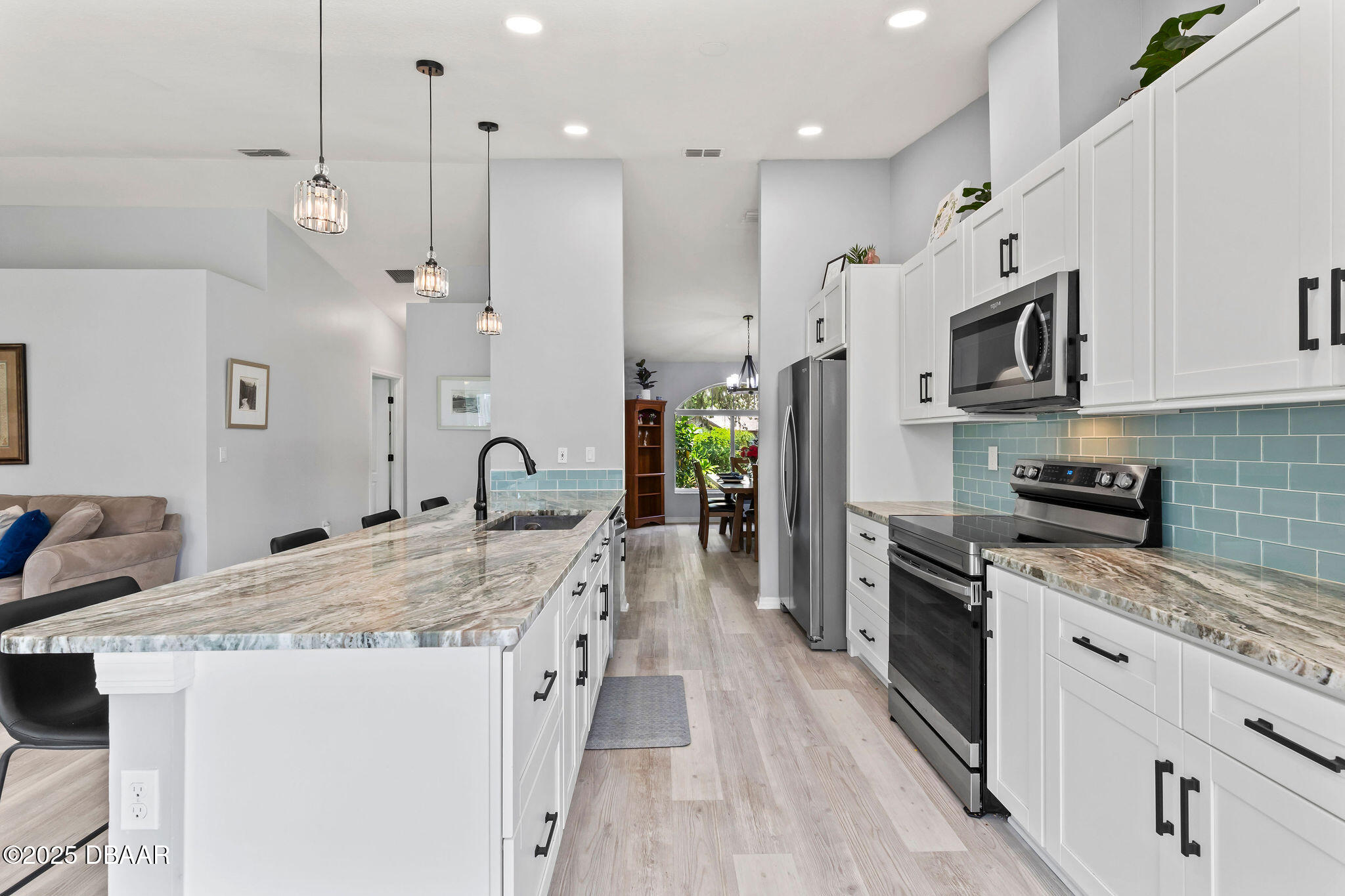 35 China Moon Drive Ormond Beach, FL 32174 - Photo 12 of 40 a large kitchen with stainless steel appliances kitchen island granite countertop a stove a sink a refrigerator and a dining table with wooden floor