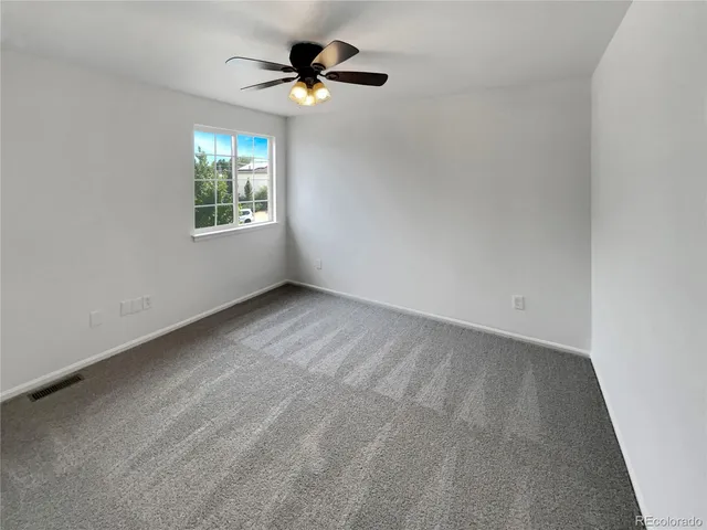 an empty room with a window and a fan
