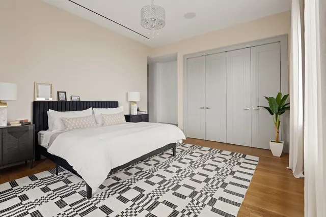 a bedroom with a bed and a potted plant on the dresser