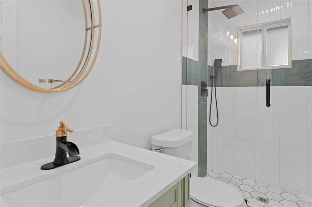 4606 Hazelhurst Lane Dallas, TX 75227 - Photo 23 of 30 a bathroom with a sink a toilet and a mirror