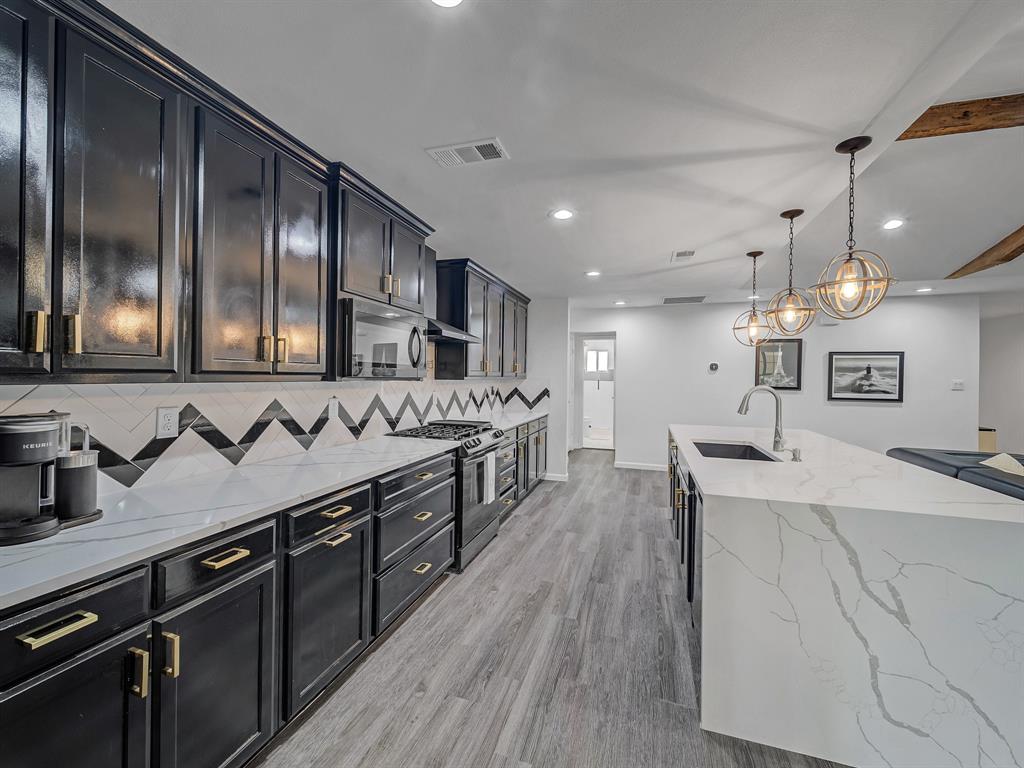 4606 Hazelhurst Lane Dallas, TX 75227 - Photo 7 of 30 a large kitchen with stainless steel appliances a sink a stove and a wooden floors