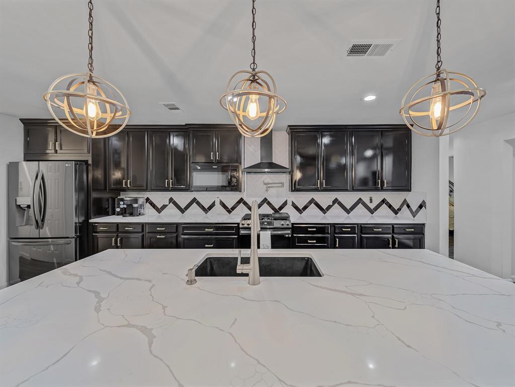 4606 Hazelhurst Lane Dallas, TX 75227 - Photo 9 of 30 a kitchen with stainless steel appliances granite countertop a stove a refrigerator and chandelier