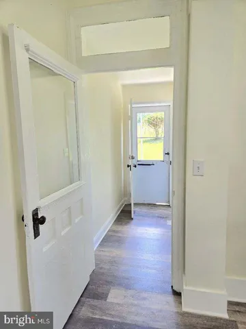 a view of a hallway with wooden floor and a bathroom