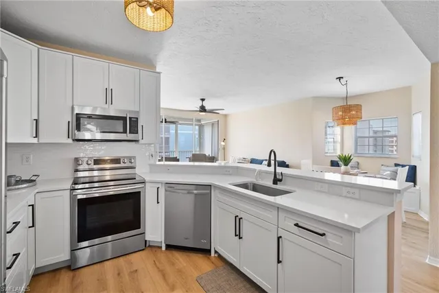 a kitchen with stainless steel appliances kitchen island granite countertop a dining table chairs and a refrigerator
