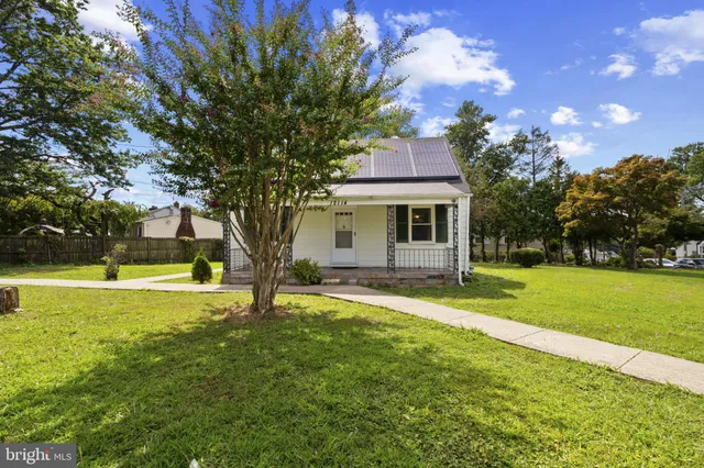 a view of a house with a big yard and large tree
