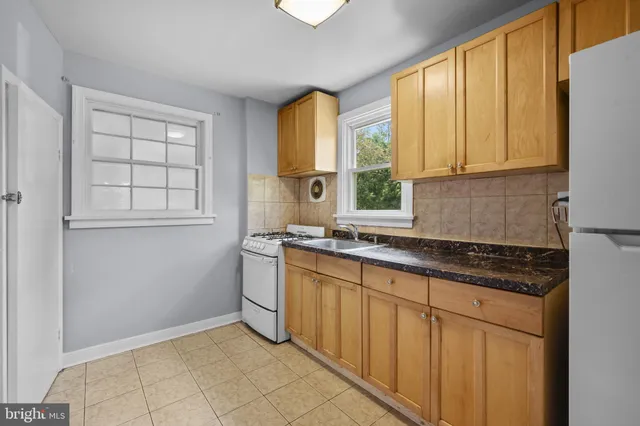 a kitchen with granite countertop a sink window and cabinets