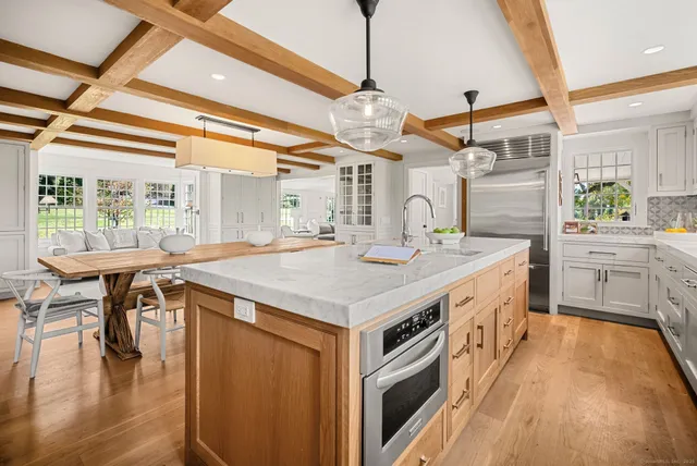 a kitchen with a stove a sink a window and chairs