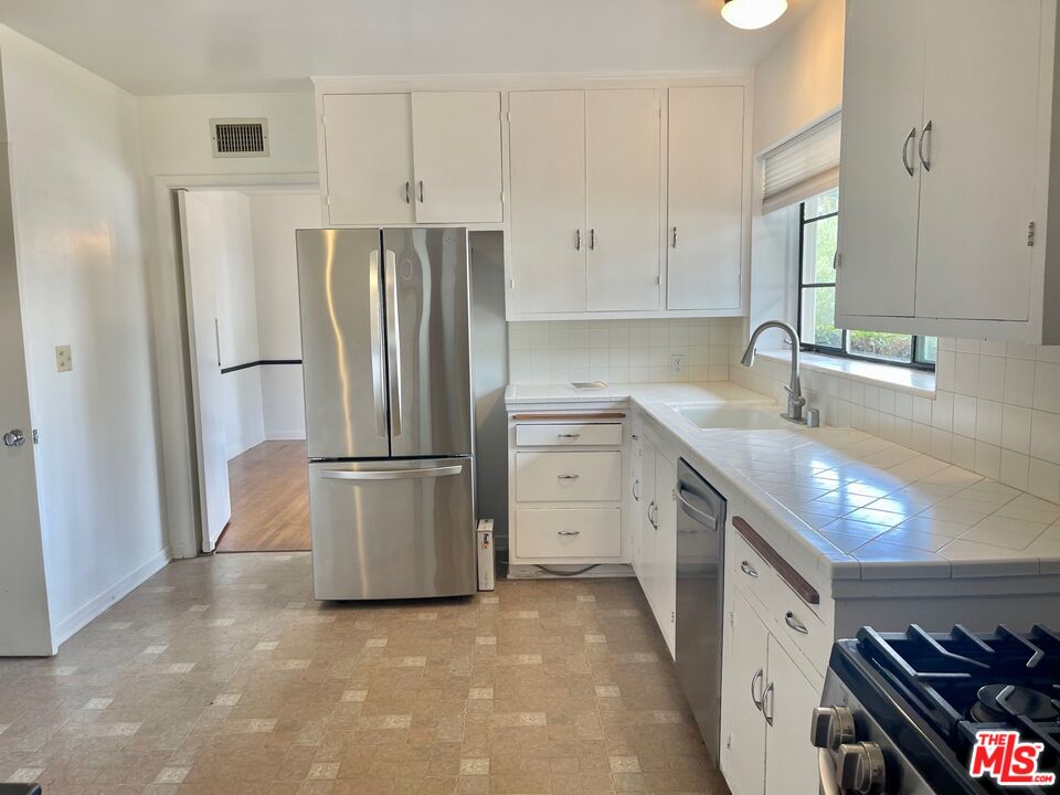 101 Larkin Place Santa Monica, CA 90402 - Photo 8 of 13 a kitchen with stainless steel appliances a refrigerator sink and cabinets