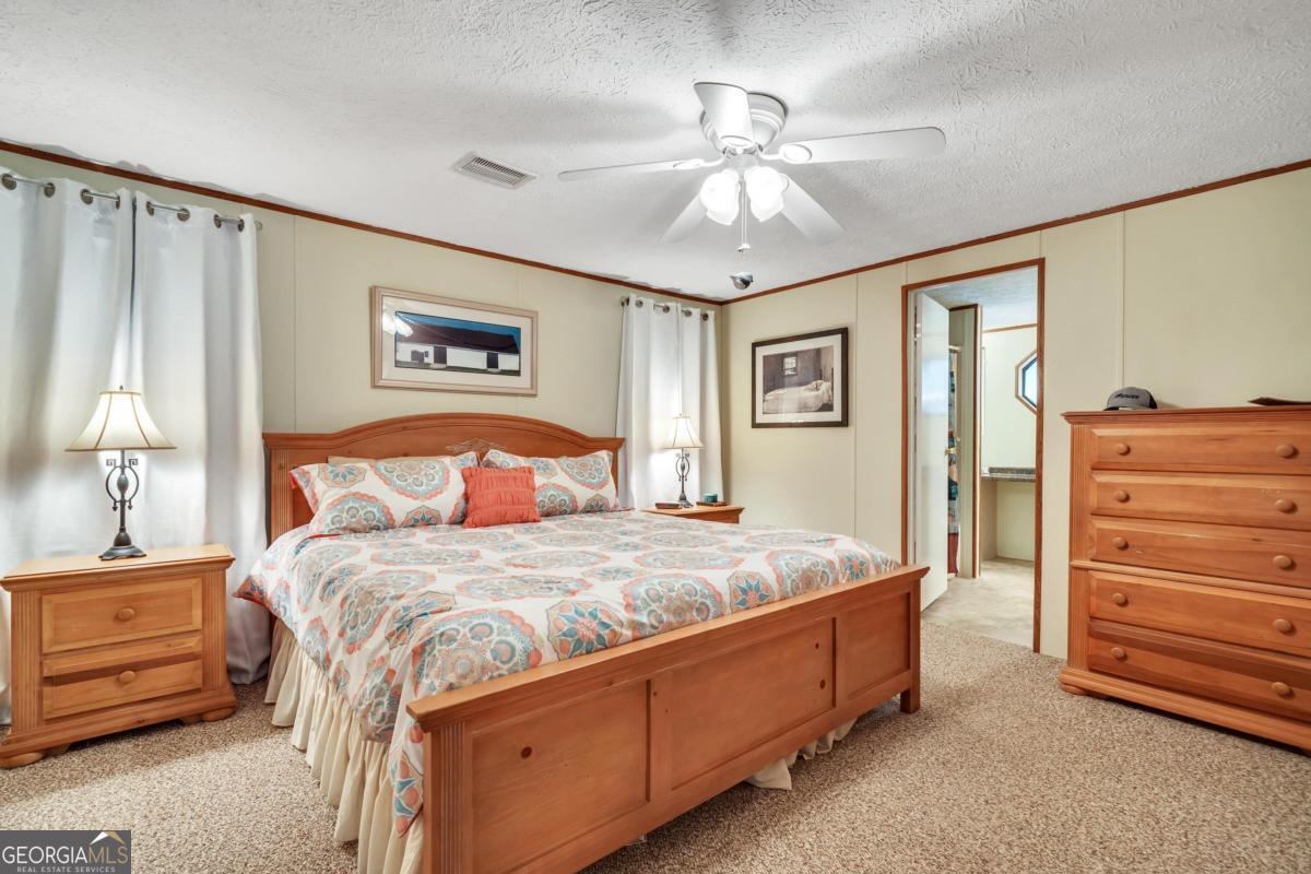 180 De Jarnette Road Southeast Eatonton, GA 31024 - Photo 19 of 66 a bedroom with a bed and a chandelier