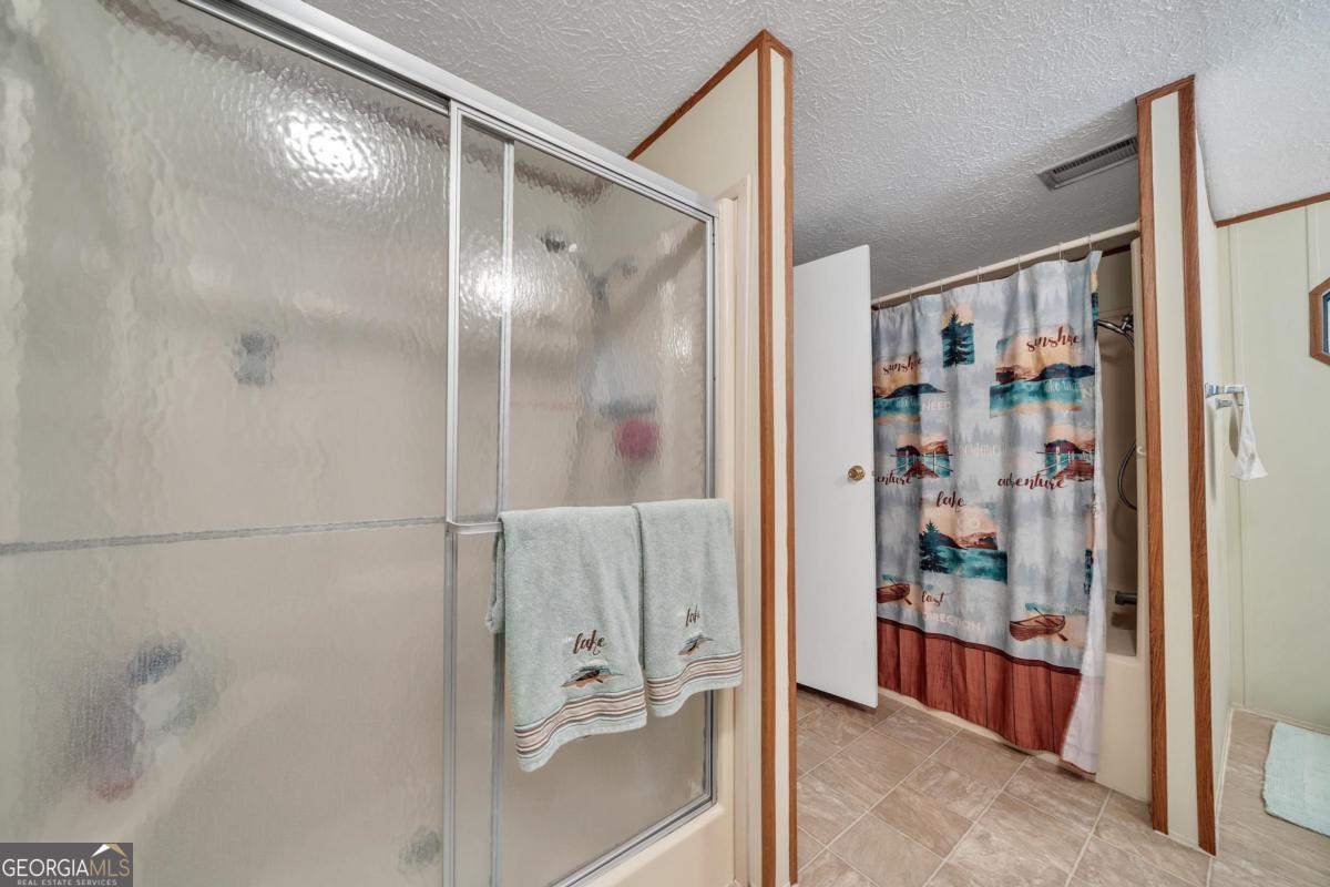 180 De Jarnette Road Southeast Eatonton, GA 31024 - Photo 21 of 66 a bathroom with a glass shower door