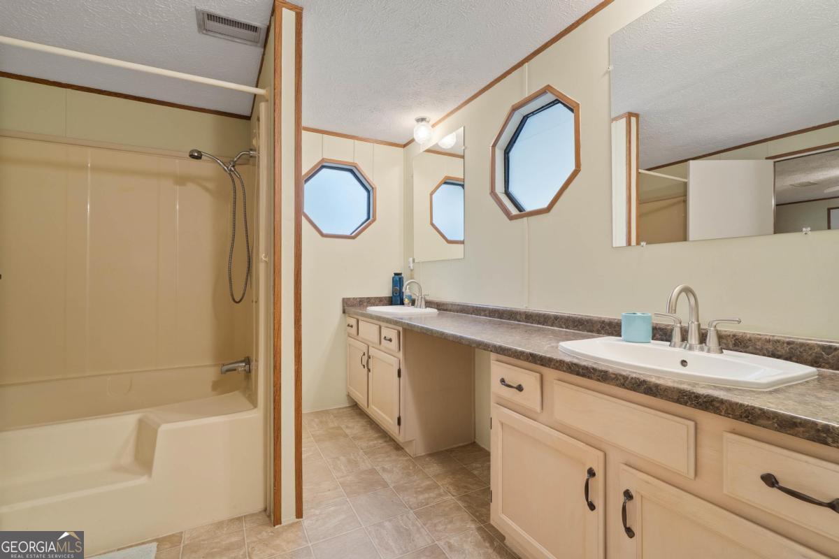 180 De Jarnette Road Southeast Eatonton, GA 31024 - Photo 23 of 66 a bathroom with a double vanity sink mirror and bathtub