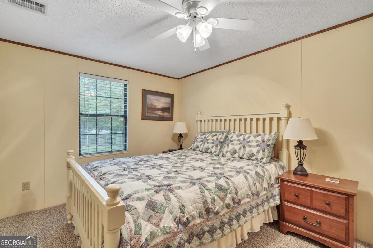 180 De Jarnette Road Southeast Eatonton, GA 31024 - Photo 26 of 66 a bedroom with a bed and a dresser