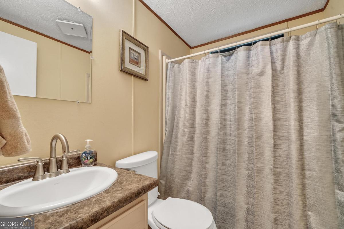 180 De Jarnette Road Southeast Eatonton, GA 31024 - Photo 28 of 66 a bathroom with a granite countertop sink and a mirror