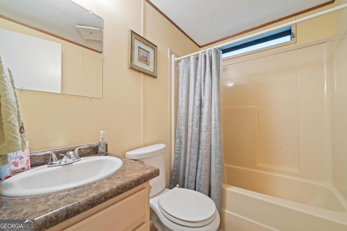 180 De Jarnette Road Southeast Eatonton, GA 31024 - Photo 29 of 66 a bathroom with a granite countertop sink toilet and shower