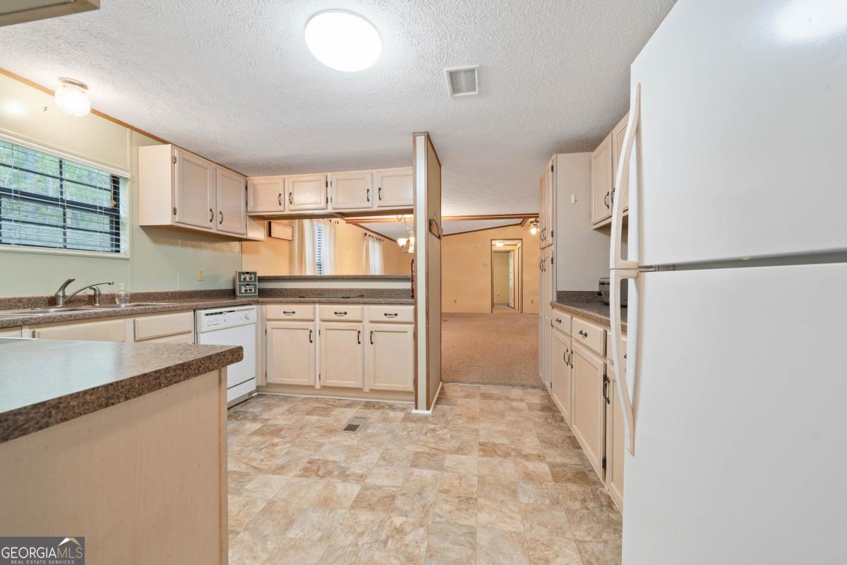 180 De Jarnette Road Southeast Eatonton, GA 31024 - Photo 5 of 66 a kitchen with white cabinets and refrigerator