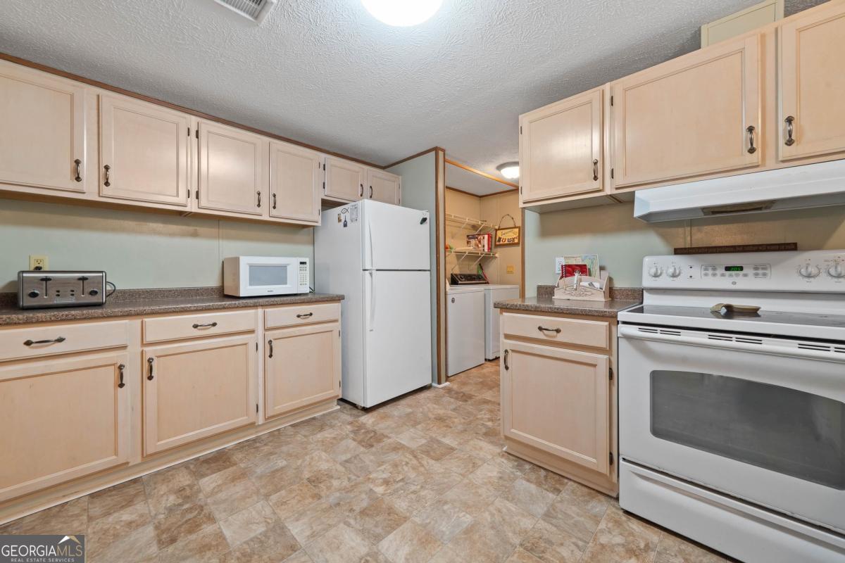 180 De Jarnette Road Southeast Eatonton, GA 31024 - Photo 8 of 66 a kitchen with cabinets stainless steel appliances and sink