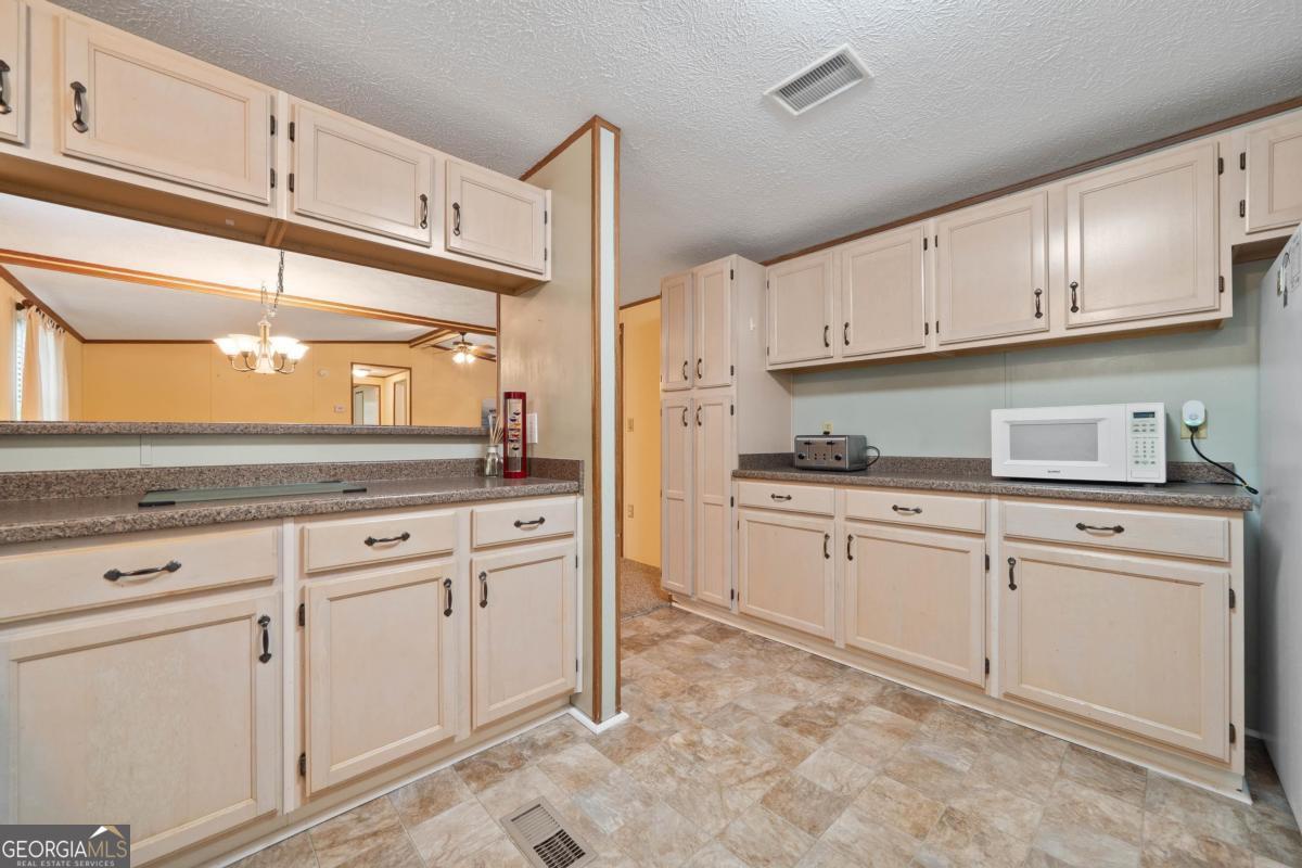 180 De Jarnette Road Southeast Eatonton, GA 31024 - Photo 9 of 66 a kitchen with granite countertop white cabinets and white appliances