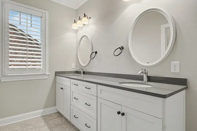 a bathroom with a granite countertop double vanity sink and a mirror