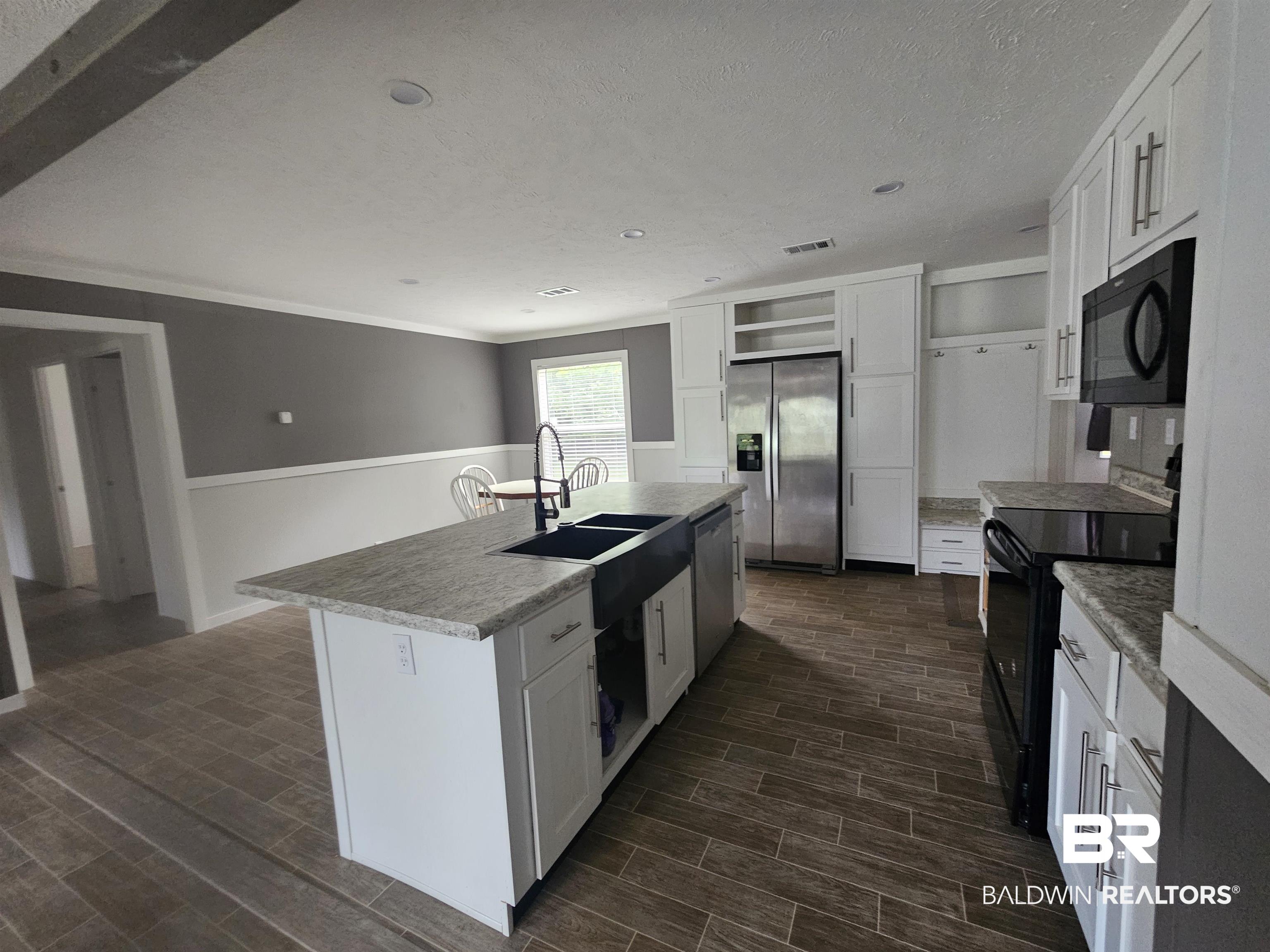 1863 Wait Road Monroeville, AL 36460 - Photo 4 of 38 Kitchen with sink, black appliances, a center island with sink, and white cabinets