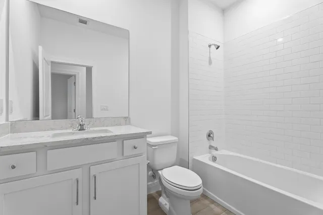 a bathroom with a granite countertop toilet a sink and a bathtub