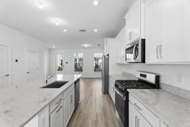 a kitchen with granite countertop a sink stove and cabinets