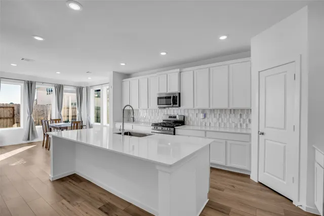 a large white kitchen with lots of counter space a sink and appliances