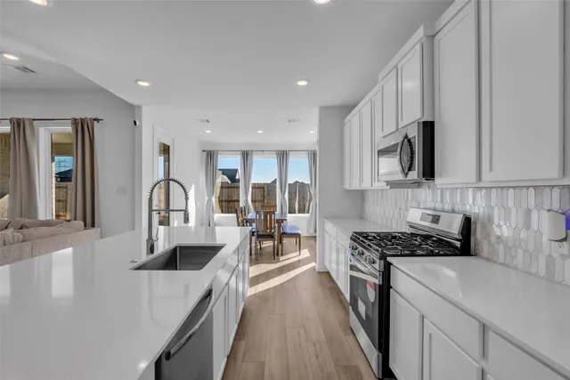 a kitchen with kitchen island a white counter top space a stove a sink a refrigerator and cabinets