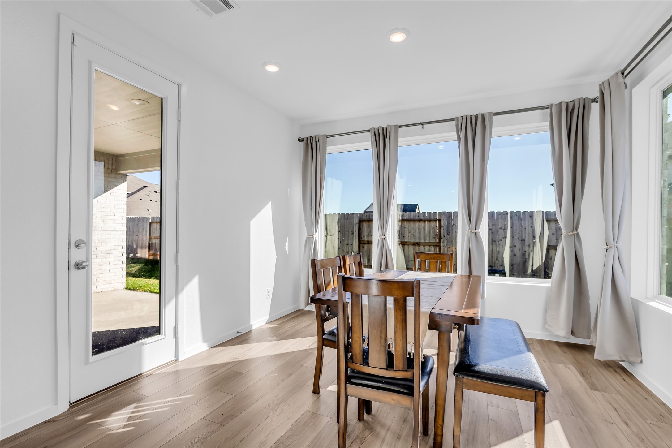 8619 Jade Hl Drive Rosharon, TX 77583 - Photo 24 of 50 Dining Area: Bright and open with large windows that invite natural light throughout the day. The glass door to the left provides direct access to the covered patio, creating an easy indoor-outdoor flow for everyday living and entertaining.