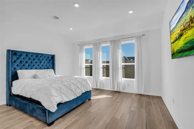 a bedroom with a large bed windows and wooden floor