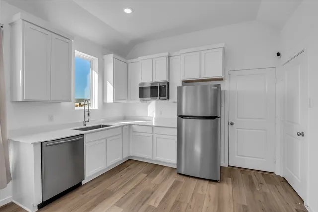 a kitchen with a refrigerator sink and cabinets