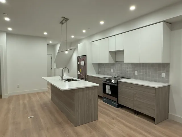 a kitchen with stainless steel appliances granite countertop a sink a stove and a wooden floors