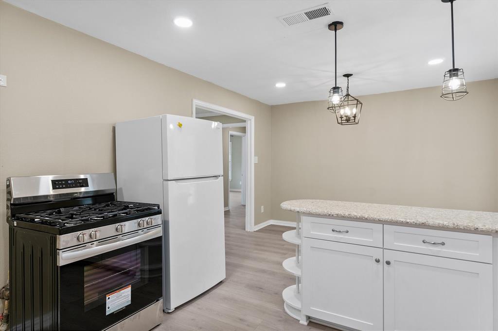 415 Maple Drive Terrell, TX 75160 - Photo 7 of 26 a kitchen with a refrigerator a stove and white cabinets