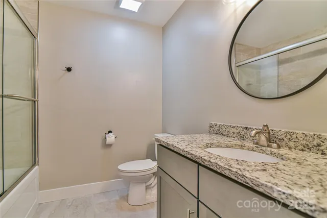 a bathroom with a granite countertop sink a toilet and a mirror