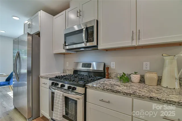 a kitchen with stainless steel appliances granite countertop a stove a microwave and cabinets