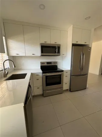 a kitchen with granite countertop a refrigerator and a sink