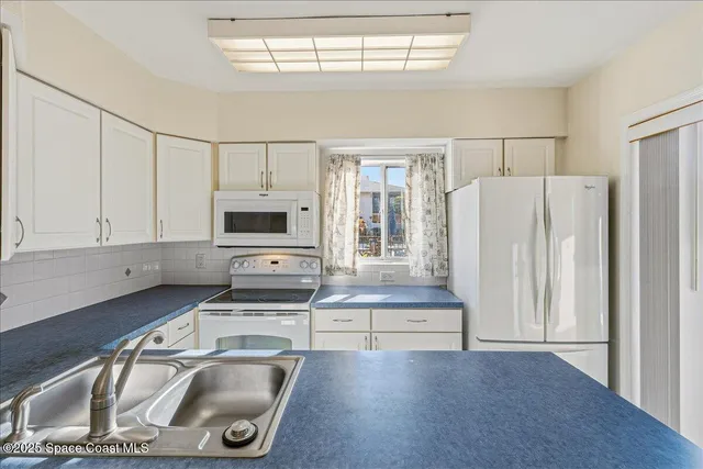a kitchen that has a stove a refrigerator and a sink with wooden cabinets