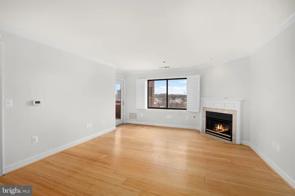 a view of an empty room with wooden floor fireplace and a window