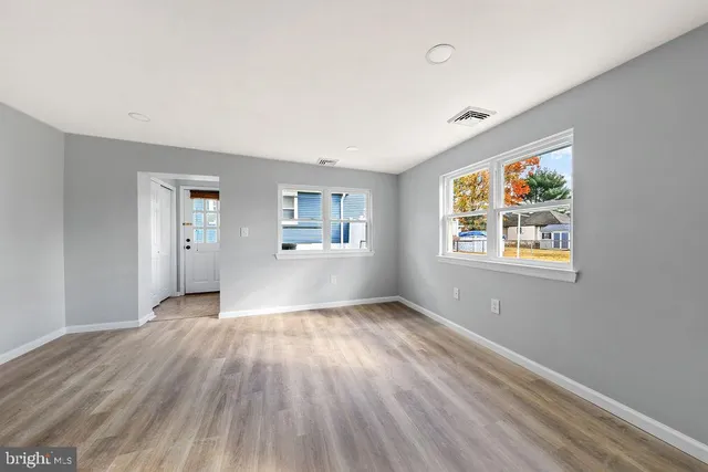 a view of an empty room with window and wooden floor